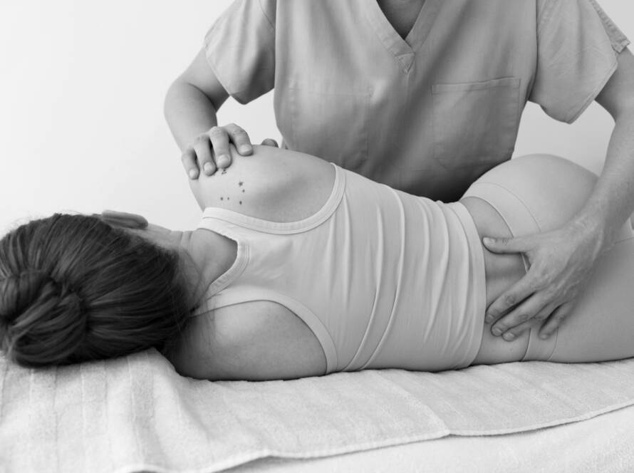 Black and white image of a woman receiving posture correcting massage therapy.