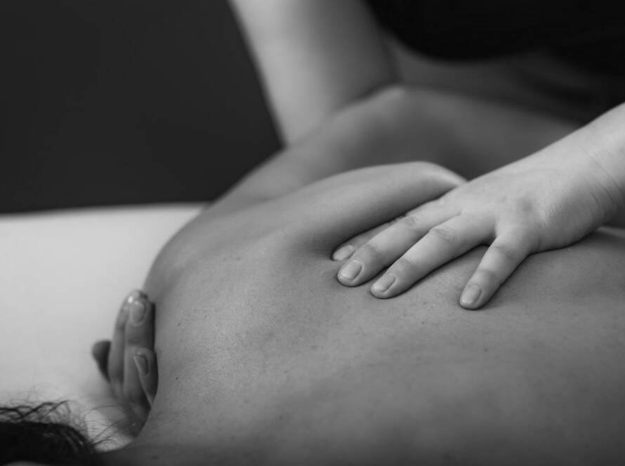 Black and white image of a client faced down, with the therapist applying the techniques of Be Activated massage therapies to improve overall function and optimal performance.